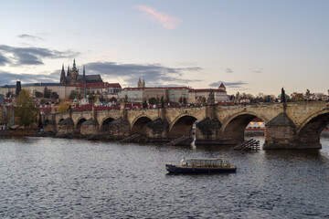 Castle of Prague and Charles bridge reflected on Vltava river at sunset