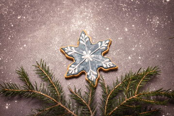 gingerbread snowflake on a dark background with fir branches and snow