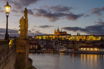 Castle of Prague and Charles bridge reflected on Vltava river at sunset