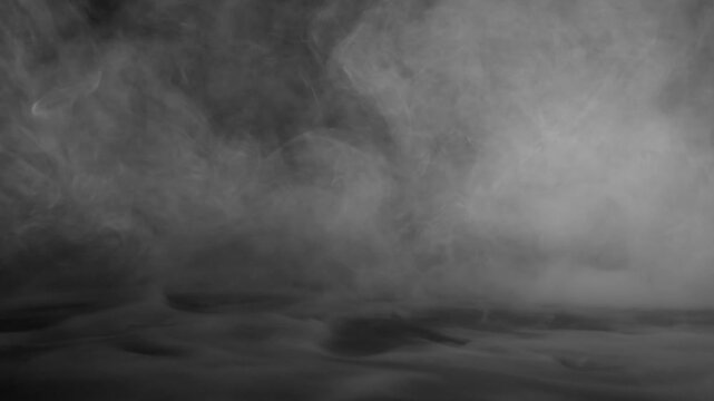 Dense white fog rolling across a dark surface smoke
