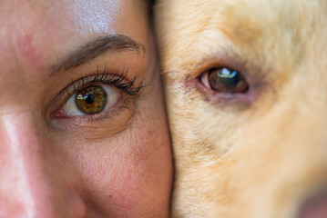 Close-up of a smiling woman with brown eyes and a golden retriever, showcasing a bond between human and pet, highlighting joy and companionship in a warm atmosphere