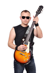 Roker in jeans and a T-shirt wearing dark glasses plays an electric guitar.