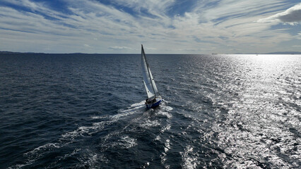 Naklejka premium Aerial drone photo of beautiful sail boat with white sails cruising deep blue waves in Aegean sea