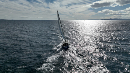 Aerial drone photo of beautiful sail boat with white sails cruising deep blue waves in Aegean sea