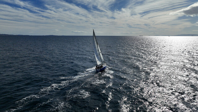 Aerial drone photo of beautiful sail boat with white sails cruising deep blue waves in Aegean sea