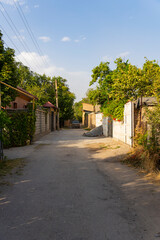 Shaded, narrow unpaved alley between tall walls