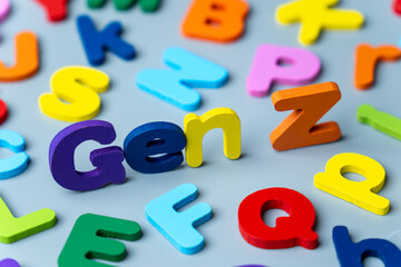 Naklejka premium The phrase GEN Z is spelled out in colorful wooden letters scattered on a gray background. Modern generation, digital natives, youth culture, demographics, and future trends concept.