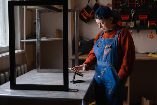 Handywoman restoring worker checking message with orders using smartphone and banking balance online while work in repair workshop - Powered by Adobe