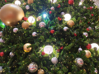 Beautifully decorated christmas tree texture features glowing light and colorful ball ornaments bringing joy to holiday season. Festive set creates perfect backdrop with copyspace for greeting