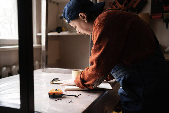 Small business concept. Handywoman measuring with tape on wooden table. Professional handy worker using tools for work in workshop.