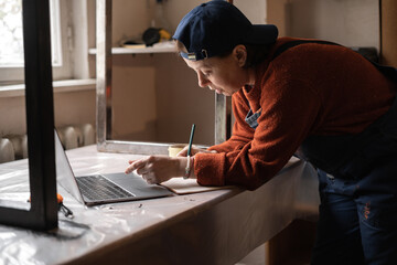Business woman or Craftswoman working using a laptop in the garage. Mechanic at workshop.