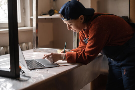 Business woman or Craftswoman working using a laptop in the garage. Mechanic at workshop.