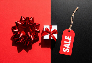 Valentines day sell flat lay with red gift bow and white present box on dual red and black background