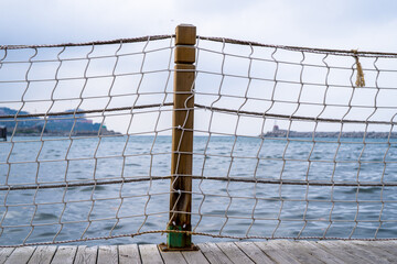 Obraz premium Wooden Post With Rope Netting At Pier Over Calm Water – A Coastal Scene