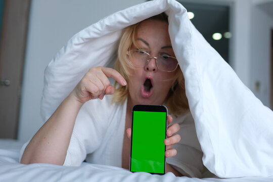 green screen for chroma key advertising Shocked lady staring at smartphone with open mouth. Middle-aged woman reading surprising message on phone, amazing news at night