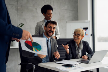 A group of business professionals is attending a presentation given by a colleague in a modern office or meeting room