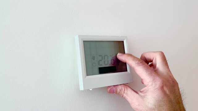 close-up of a finger raising the temperature from 18 to 20 degrees Celsius on the touchscreen of a heating thermostat, setting the comfortable temperature in the home in winter