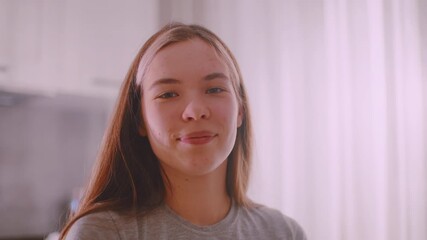 Happy young lady smiling brightly, expressing joy and contentment with natural charm, cheerful expression captured in soft indoor light, radiating positivity and youthful confidence