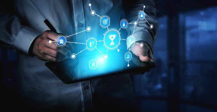 A businessman interacts with a digital tablet, showcasing connected icons that symbolize technology and achievement in a modern office setting. Innovative concepts emerge. Tessel
