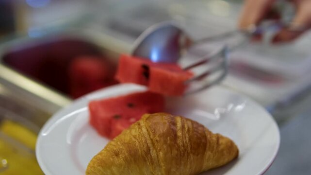Croissant watermelon fork table with breakfast served, a knife, spoon and fork of bronze color with elegant black stand out