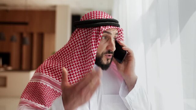 Irritated Muslim entrepreneur talking on phone, upset with failed business deal