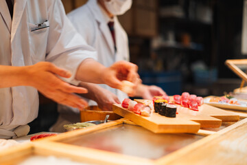 Chefs prepare sushi for customers at a restaurant