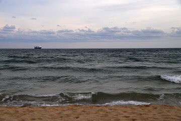 sea waves and distant ship on sandy beach
