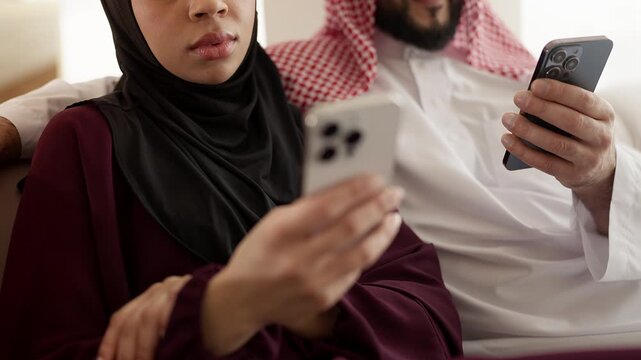 Muslim couple in traditional wear using their phones, browsing social networks