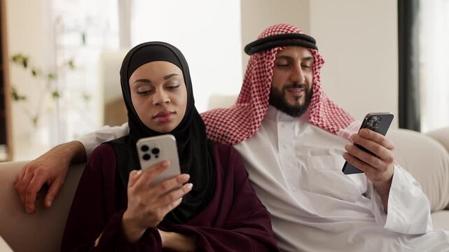 Middle Eastern woman and husband scrolling social media apps on their phones