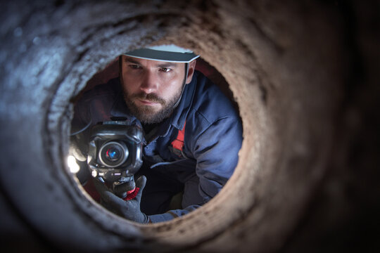 A plumber uses a specialized camera to inspect the interior of a sewer line for blockages and damage