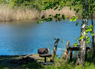 Serene summer view of a pond with a chair and table on the shore