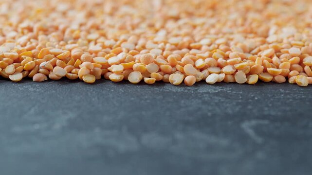 dried peas or yellow peas on a black marble background.  dry yellow peas scattered on a dark kitchen table.