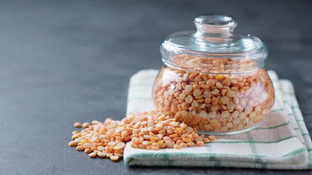 dried peas or yellow peas in glass storage jar on a black marble background.  dry yellow peas in a storage glass jar on a dark kitchen table.