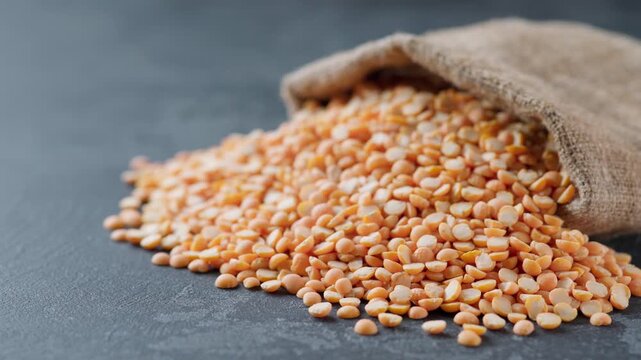 dry yellow peas in sack on a dark kitchen table. Natural yellow peas are scattered out of the bag. Sack of yellow peas spill.