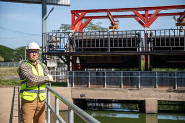 Fototapeta premium Engineer standing confidently at a hydraulic water control structure during a sunny field inspection