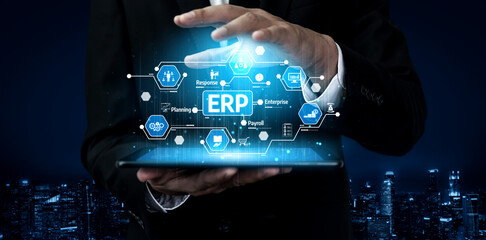 A businessman interacts with a high-tech tablet displaying a conceptual interface for ERP software,...