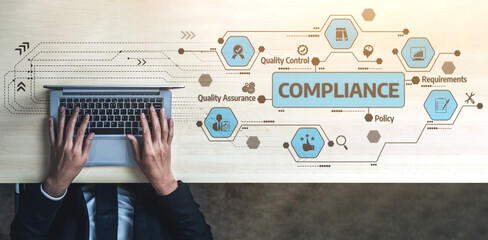 A professional workspace showcasing hands typing on a laptop with compliance terminology and graphics. Ideal for topics on quality management and business regulation. Tessel