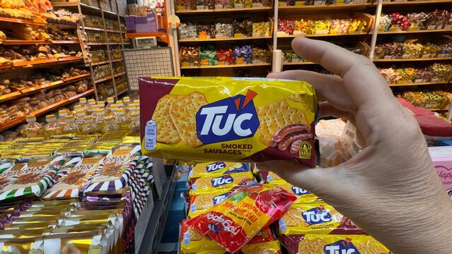 Hand holding TUC crackers in supermarket aisle, Bishkek, Kyrgyzstan 2025