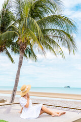 Woman relaxing on beach hammock under palm trees, tropical paradise, summer vacation concept.