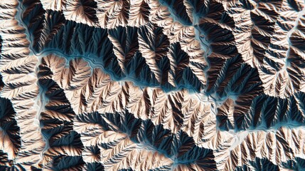 Abstract aerial view of intricate mountain formations showcasing layered terrains with contrasting tones of beige, blue, and deep shadow in a textured landscape