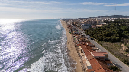Sunlit coastline and beachfront homes leading to Guardamar city skyline