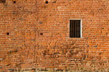 An old red brick wall with a small window