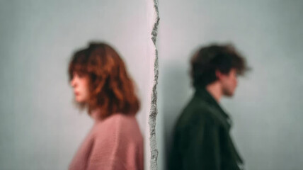 Obraz premium Young man and woman standing apart, divided by a textured wall, illustrating conflict, emotional separation, and communication issues