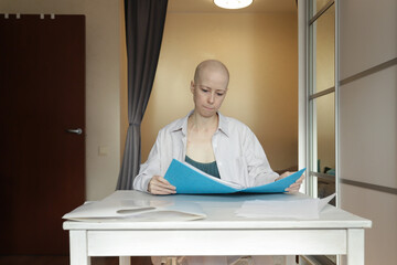 Bald woman at home table reading important documents, symbol of online consultation preparation and medical decision-making.