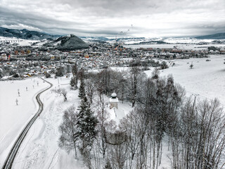 Aerial winter panorama of Ruzomberok with Calvary chapel in snowy landscape and mountain backdrop