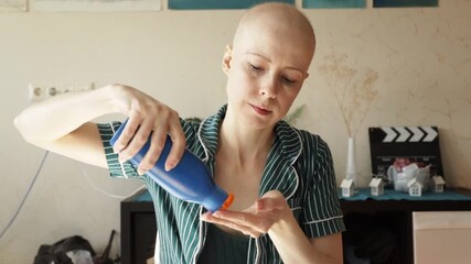 Morning self-care of a bald woman using SPF lotion and mirror, representing skincare for sensitive skin after cancer therapy