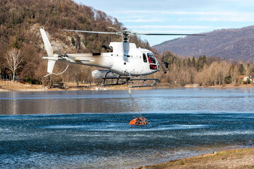 Firefighting helicopter dropping water on mountain fire above Lake Ghirla in Valganna, Province of Varese, Italy
