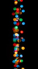 Colorful bokeh lights cascade down a black background, perfect for festive holiday designs or adding a touch of magic to your creative projects