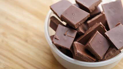 A heap of broken milk chocolate in a bowl. Close up.