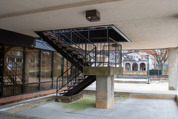 Modern concrete outdoor staircase with black metal railings leading to an upper level at a commercial building or campus